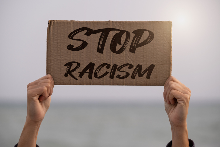 woman holding up a sign against racism