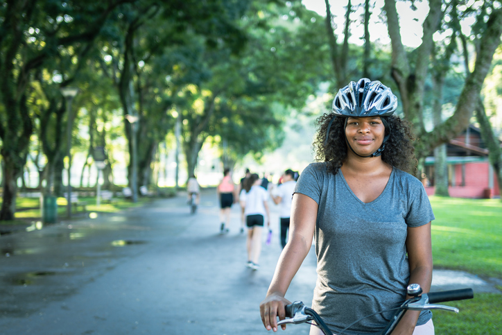 In a busy park a young woman rides her bicycle