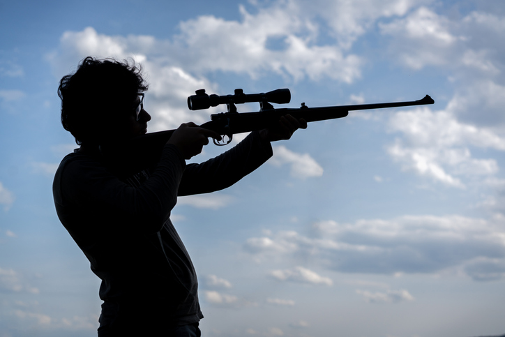 Young boy with sniper rifle outdoors