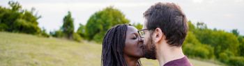 Happy multiethnic couple kissing on the hill