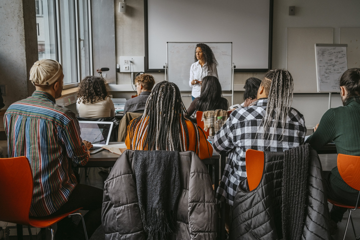 Female professor teaching university students in classroom