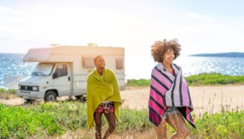 Afro couple in love enjoying their romantic summer vacation with camper