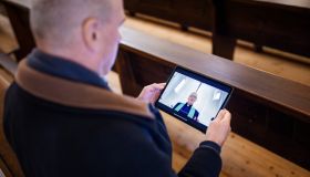 Senior man watching priest sermon online on digital tablet