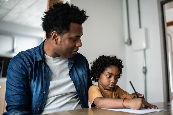 Father helping son drawing/writing at home
