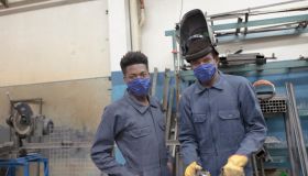 Portrait of two black workers on a grid with face mask at reopening factory.