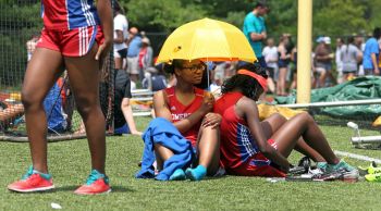 (051715 Newton, MA) Iodine Felix and Lourdes Jean-Louis (cq) of Somerville hide from the hot sun under an umbrella as they wait for their race during the Division 1 state track relays at Newton SouthHigh School in Newton. (Sunday,May 17, 2015). Staf
