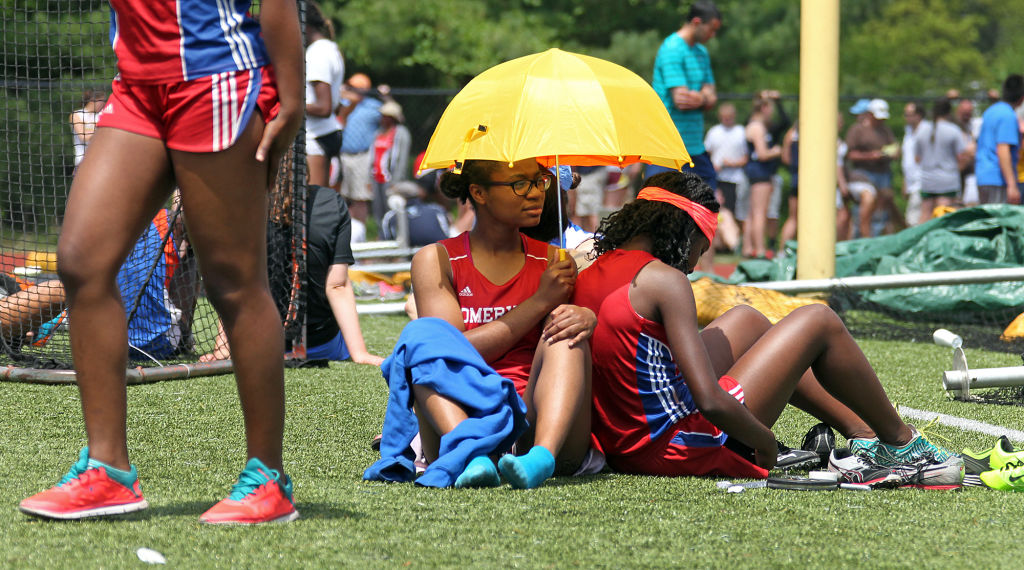 (051715 Newton, MA) Iodine Felix and Lourdes Jean-Louis (cq) of Somerville hide from the hot sun under an umbrella as they wait for their race during the Division 1 state track relays at Newton SouthHigh School in Newton. (Sunday,May 17, 2015). Staf