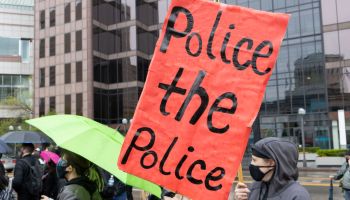 Black Lives Matter activist holds sign reading "police the...