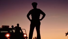 Silhouette of policemen with police car in background
