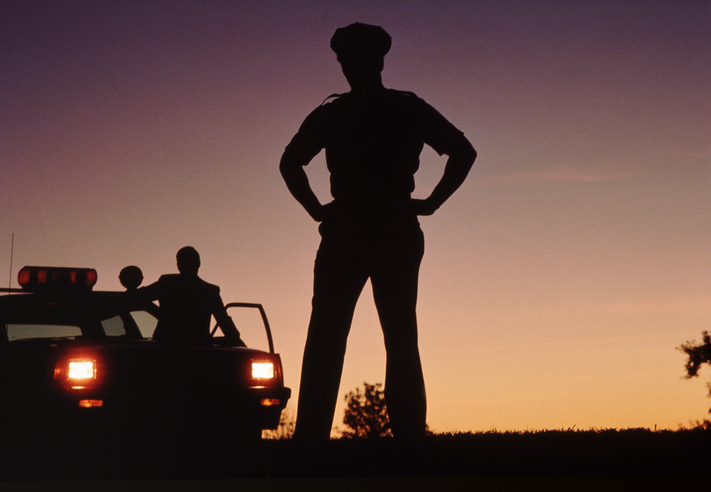 Silhouette of policemen with police car in background