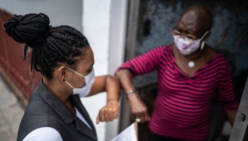 Surveyor greeting senior woman in the doorway - wearing face mask