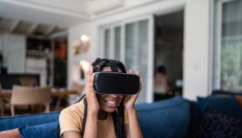 Teenage girl playing using VR glasses at home