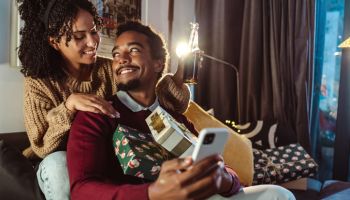 Young couple taking a selfie with Christmas present during winter holidays