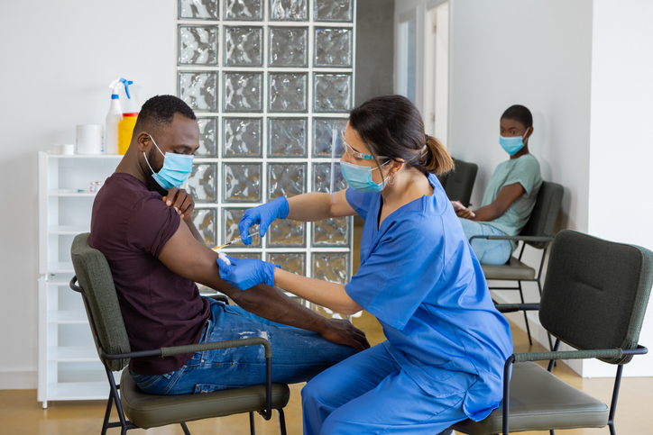 Black man with face mask being vaccinated