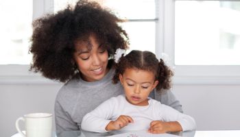 African American young mother with daughter drawing together