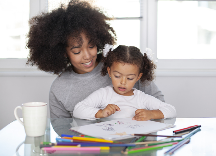 African American young mother with daughter drawing together