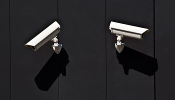 two surveillance cameras on the wall of a public building