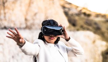 Elegant woman dressed in a white suit using a virtual reality goggles