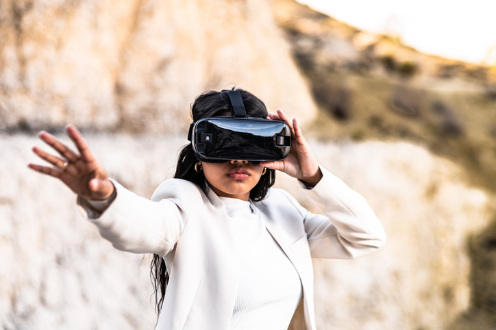 Elegant woman dressed in a white suit using a virtual reality goggles