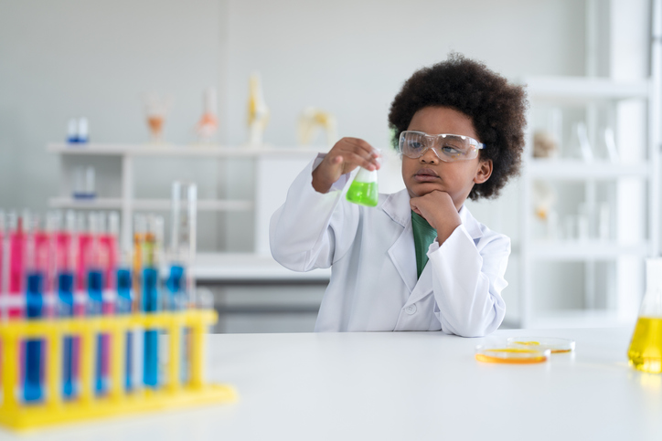 African elementary science student using chemistry set in elementary science classroom.