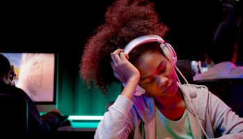 Young African American woman wearing headset play video game and live streaming online while defeat and sad at home, gaming and esport or casting game, broadcast and entertainment concept.