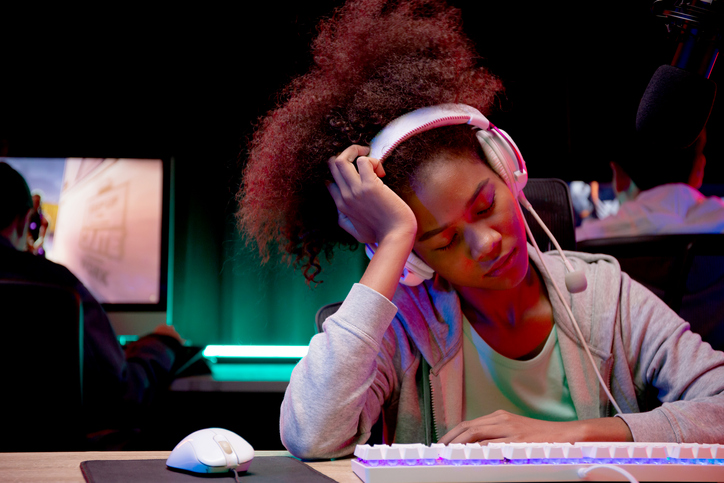 Young African American woman wearing headset play video game and live streaming online while defeat and sad at home, gaming and esport or casting game, broadcast and entertainment concept.