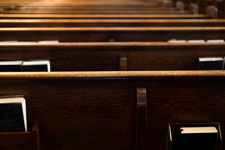rear view of rows of wooden pews with religious liturgy books stored in pew racks in church