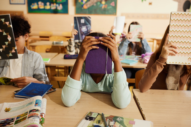 Elementary students hiding their faces on a class.