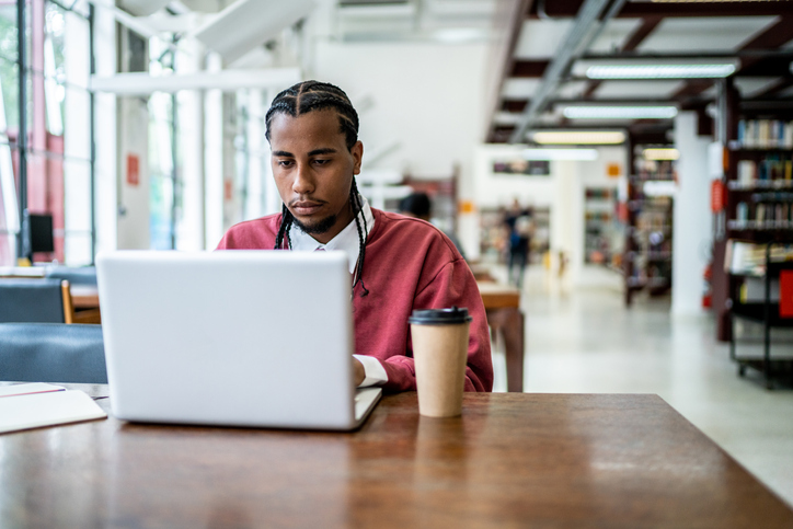 Man studying using laptop in a library
