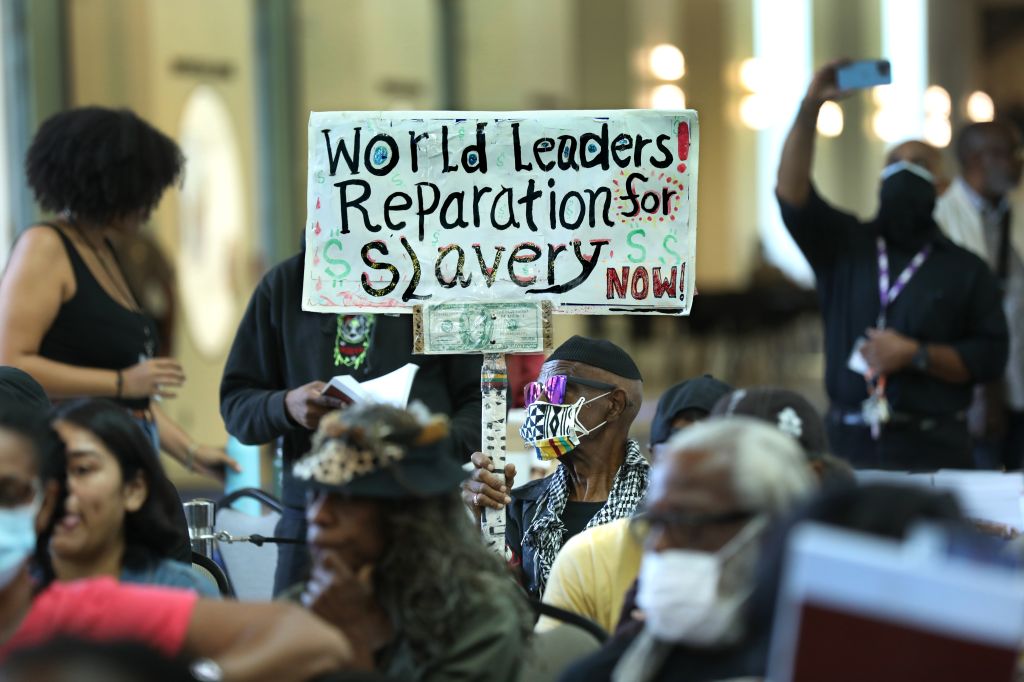 Los Angeles long-time resident, holds up a sign as the Reparations Task