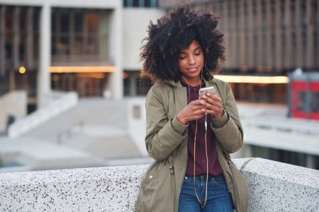 Black woman, city and texting with afro, smartphone ux and reading for social network chat. Urban gen z girl, african and phone for blog, post and networking on dating app on rooftop balcony in metro