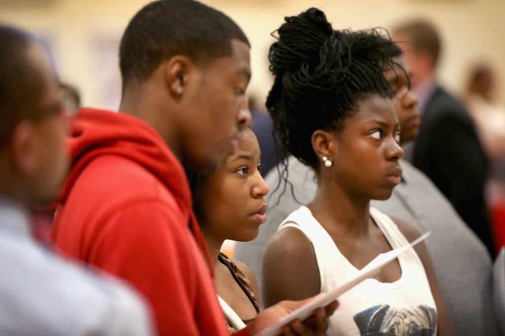 Job seekers listen to a recruiter at a job fair