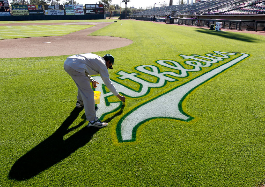 A's ground crew member Santiago Rodriguez puts finishing touches on the logo behind home plate just before the start of morning workouts as the Oakland Athletics prepare to take on the Texas Rangers on Thursday Mar. 14, 2013, in Phoenix, Az., in Spring Tr