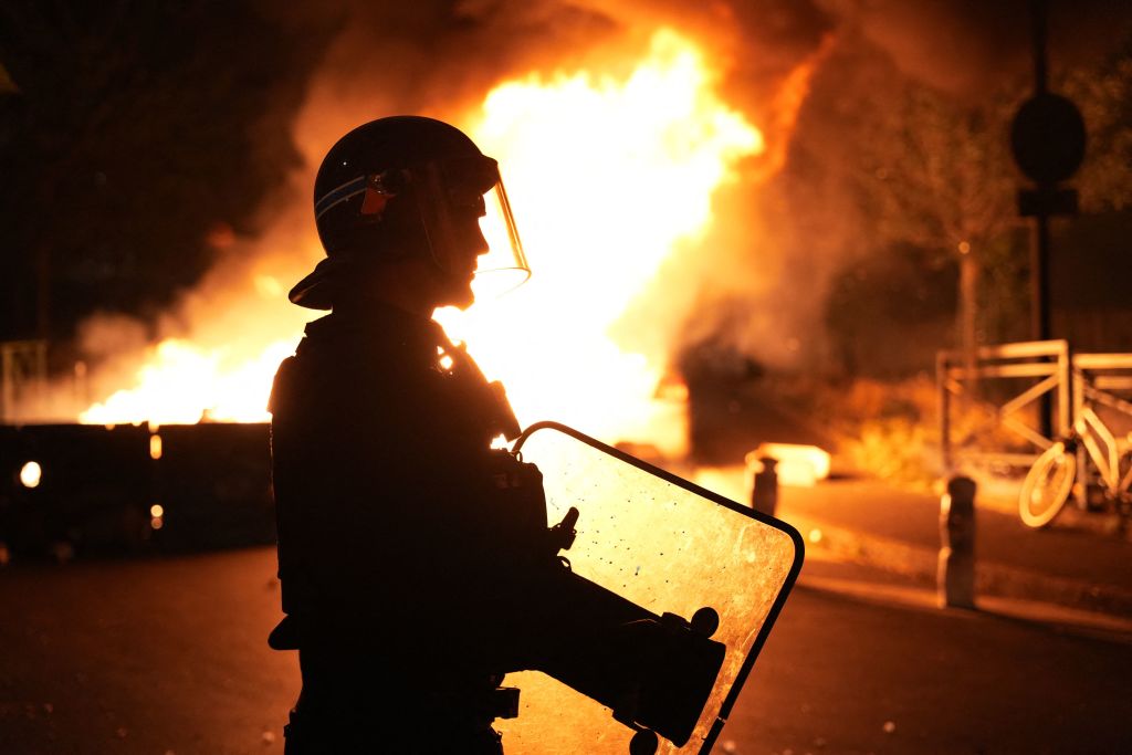 A firefighter looks on as vehicles burn