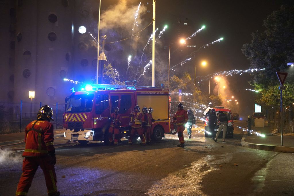 Fireworks explode as firefighters stand by during protests in Nanterre, west of Paris