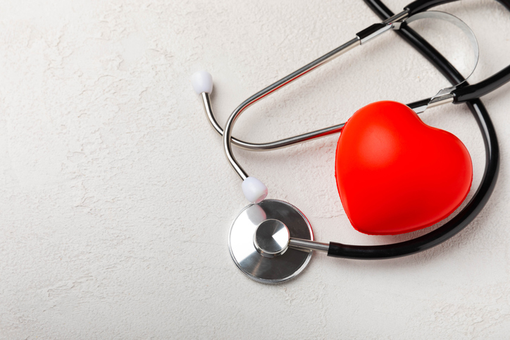 Black stethoscope and red heart, on a white textural background, close-up. Healthcare. Place for text. Medicine concept. The concept of cardiology.