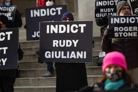 Activist holding a placard indict Rudy Giuliani. Activists...