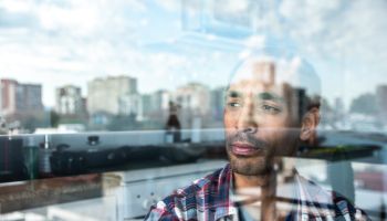 Mature man contemplating while look through window at home