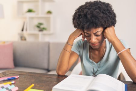 Tired young black woman reading a book