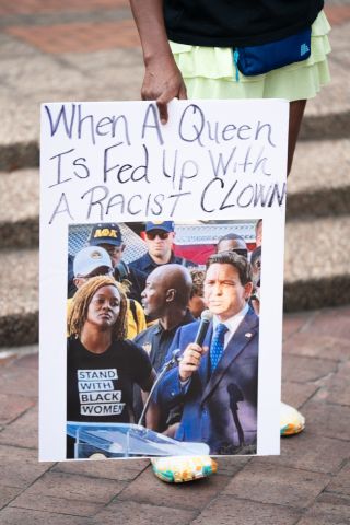 A demonstrator holds a sign with a photo of Florida Gov. Ron Desantis