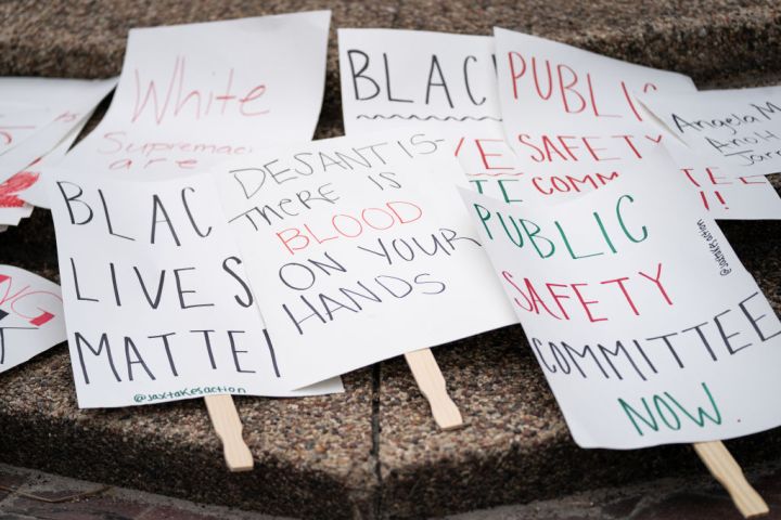 Protest signs sit on the ground before a rally against white supremacy