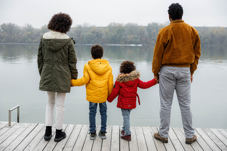 Rear view of a black family on a pier at river.