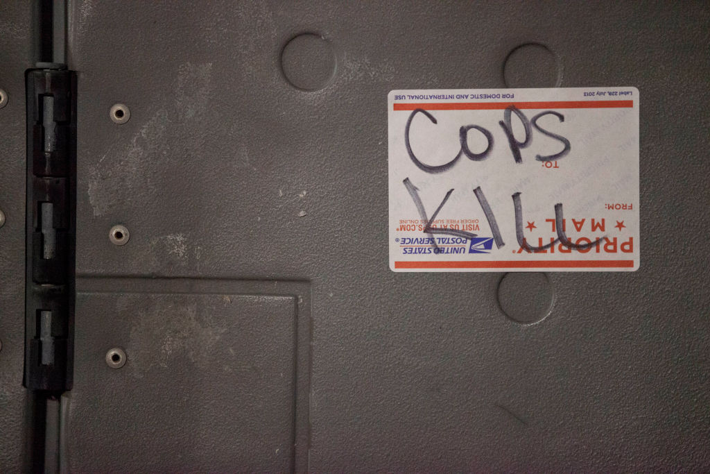 "Cops Kill" is scrawled on a United States Postal Service...