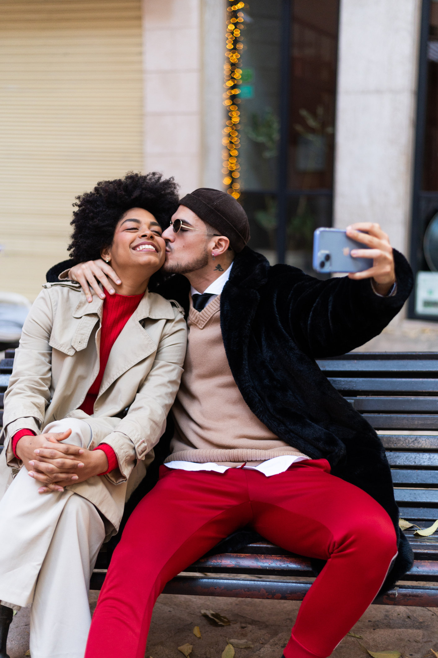 Multi-ethnic couple kissing while taking a selfie in the city