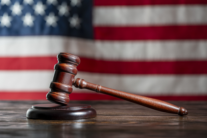 Wooden judge gavel and soundboard on the American flag background, closeup