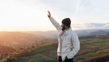 happy handsome man tourist with backpack hiking and enjoying mountains landscape at sunset in England. A trip to the mountains with a backpack. Enjoy hiking and exploring new places concept