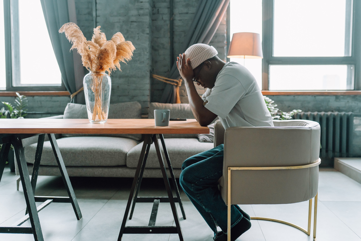 Burnt out depressed man sitting at the table with his head in his hands