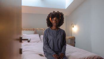 Depressed African American young woman sitting on the bed