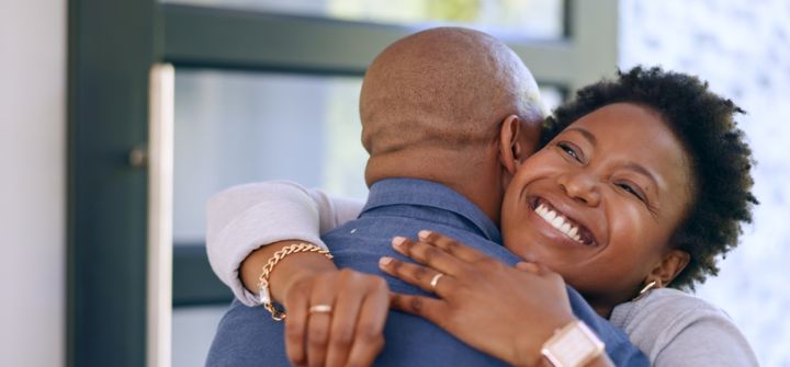 Couple, hug and key in new home or happy for real estate, property investment or celebration by front door. Black people, man and woman with embrace for fresh start, achievement and mortgage or smile