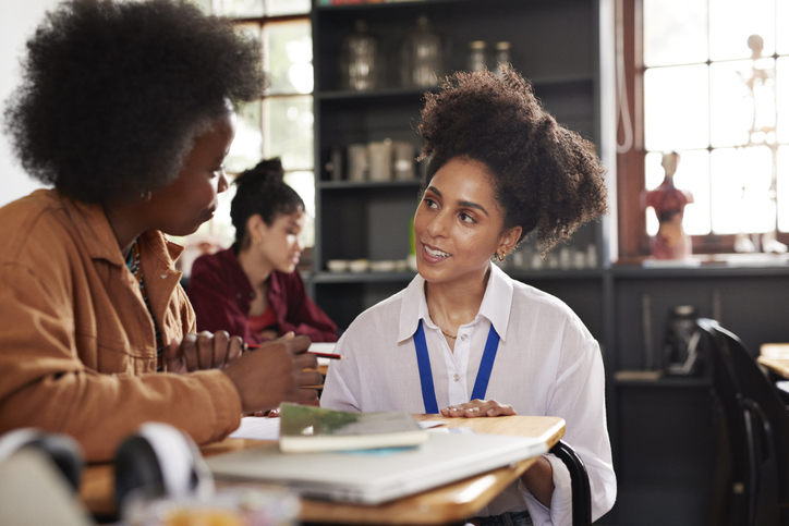 Smiling teacher helping teenage female student